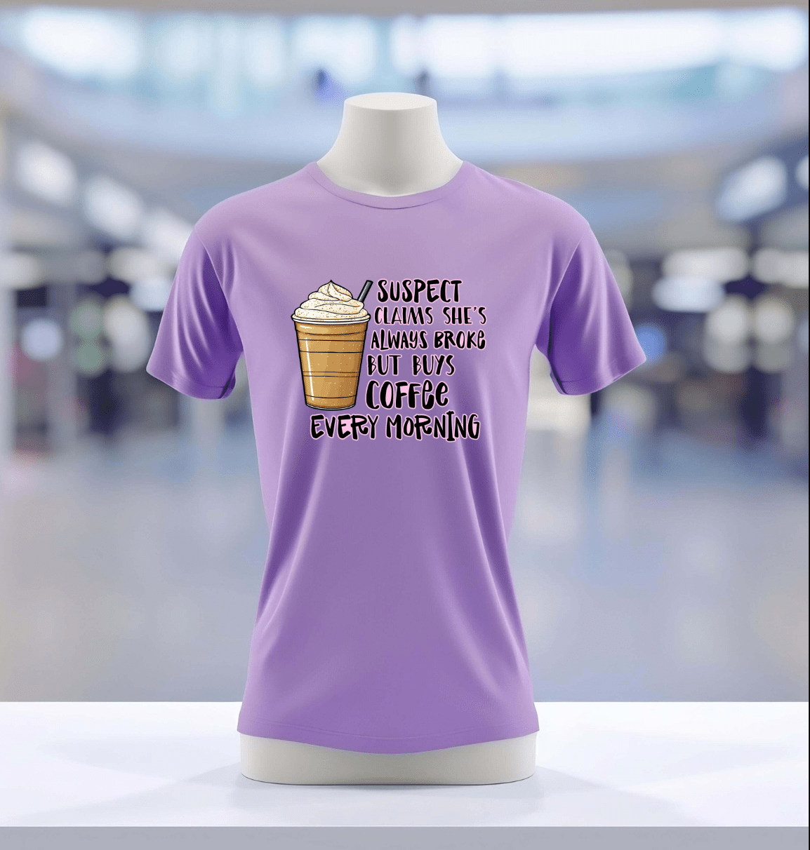 The Suspect Claims Their Broke lavender tee by DB Custom Creations features a vibrant iced coffee graphic and playful text, showcased on a mannequin in a blurred indoor setting.