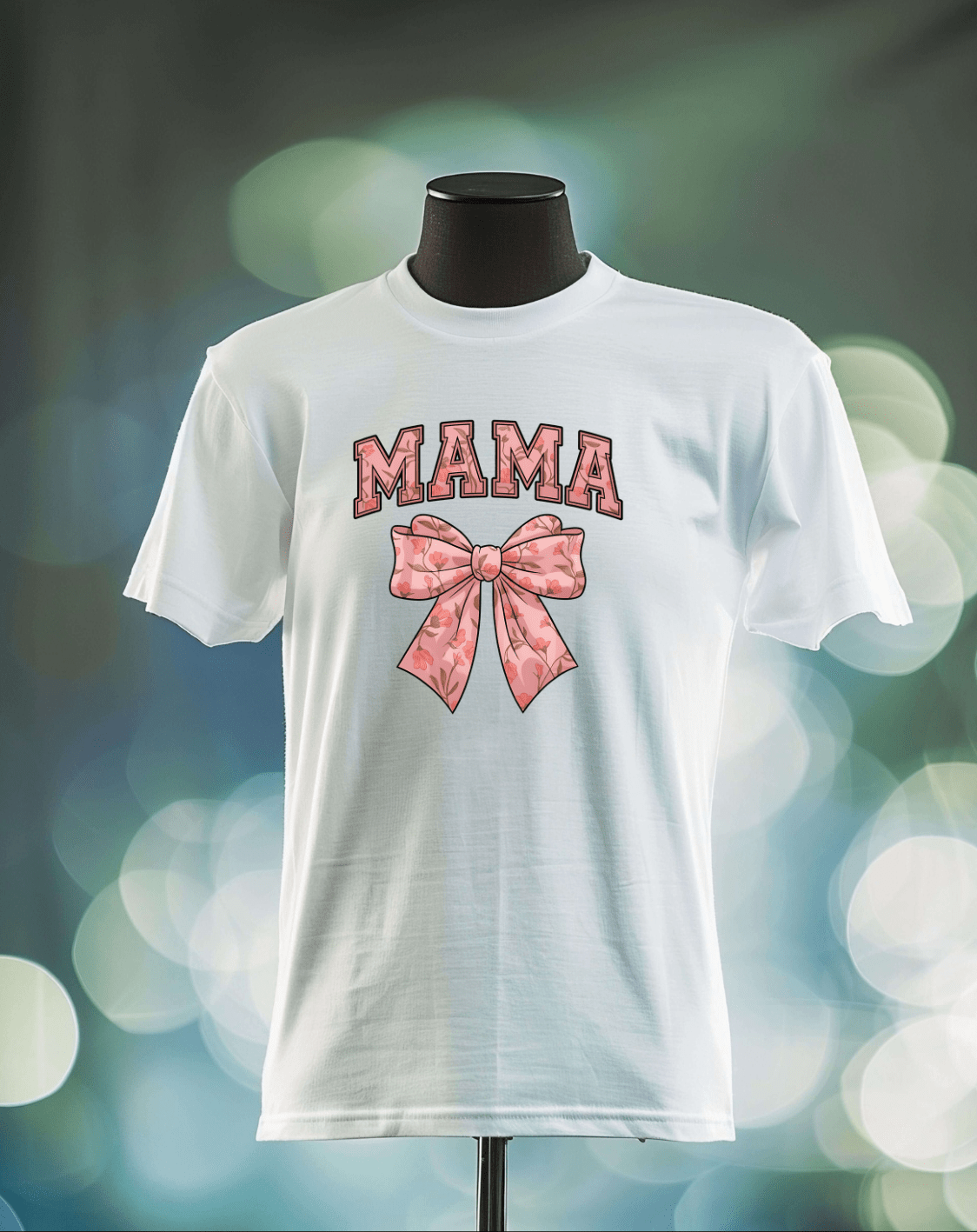 The Mama Bow t-shirt by DB Custom Creations is displayed on a mannequin, featuring bold, patterned pink MAMA lettering above a pink bow, printed with vibrant DTF Transfer, set against a softly blurred background with bokeh.