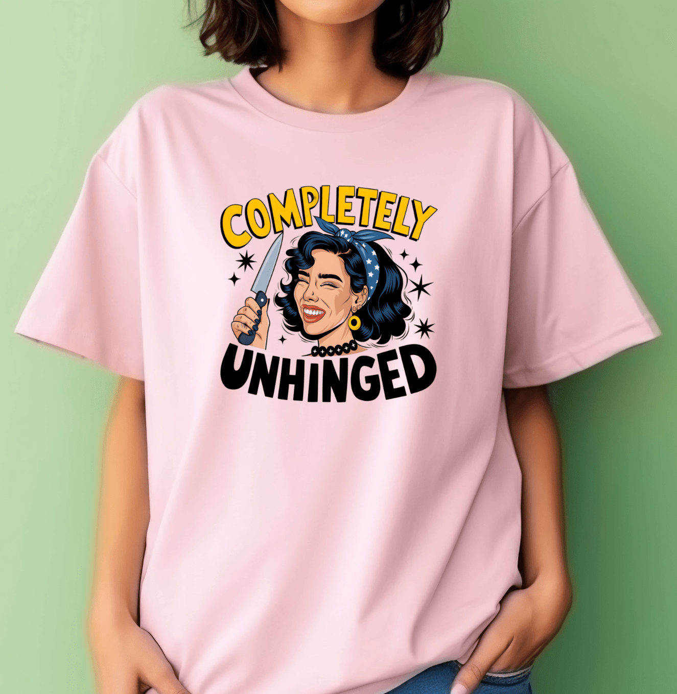 A woman wears DB Custom Creations Unhinged pink T-shirt, featuring a cartoon retro-style woman with a knife, star accents, and Completely Unhinged in bold yellow and black. Durable DTF printing ensures vibrant, lasting color.