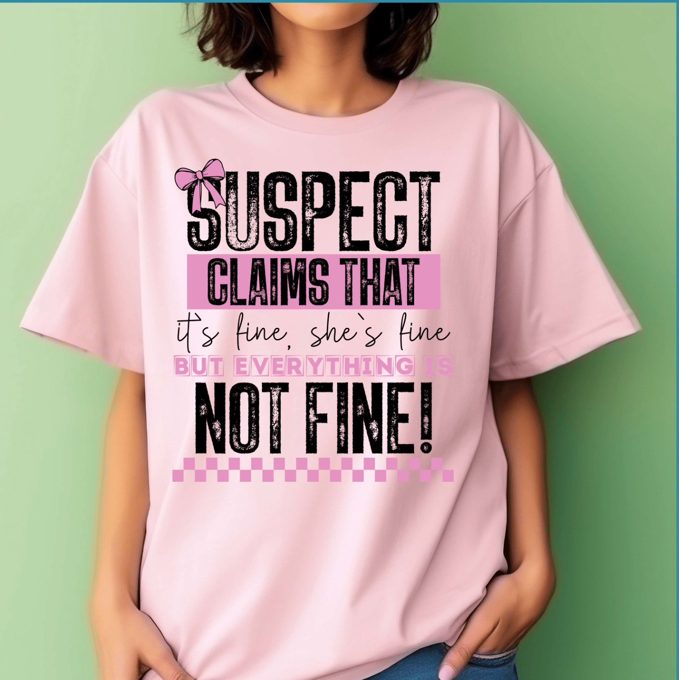 A woman wears a light pink T-shirt from DB Custom Creations, featuring the “Suspect Claims She is Fine” design in bold decorative fonts with a bow graphic and pink accents, made using 11 inch DTF transfers.