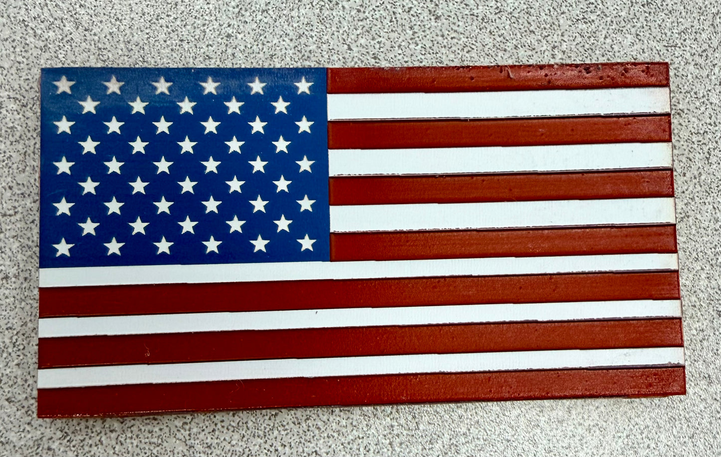 The US Flag by DB Custom Creations, featuring red and white stripes with a blue field and white stars, is displayed on a speckled gray surface next to high quality patches.