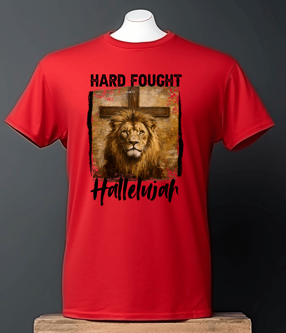The Hard Fought red t-shirt by DB Custom Creations features a lion before a wooden cross in bold 11 DTF print, with HARD FOUGHT above and Hallelujah below the image in artistic fonts.