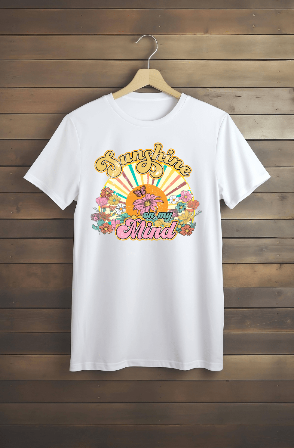 The “Sunshine” white T-shirt by DB Custom Creations features a vibrant 11-inch DTF print with retro flowers, a sun, and the phrase “Sunshine on my Mind” in yellow and pink decorative fonts.
