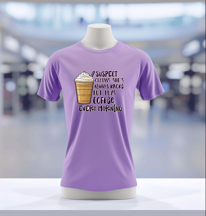 The Suspect Claims Their Broke lavender tee by DB Custom Creations features a vibrant iced coffee graphic and playful text, showcased on a mannequin in a blurred indoor setting.