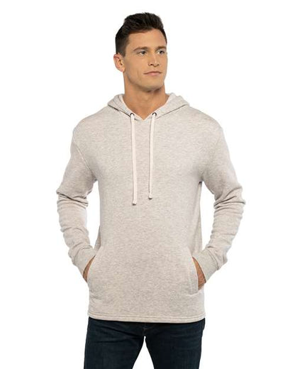 A man wears the Next Level 9300—a light gray cotton-polyester fleece hoodie with front pockets and drawstrings—crafted through socially conscious manufacturing, standing with hands in his pockets and looking slightly to the side.