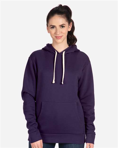 A person with long brown hair in a ponytail wears a Next Level 9303 dark purple cotton-polyester hoodie with white drawstrings and a front pocket, standing against a plain light background.
