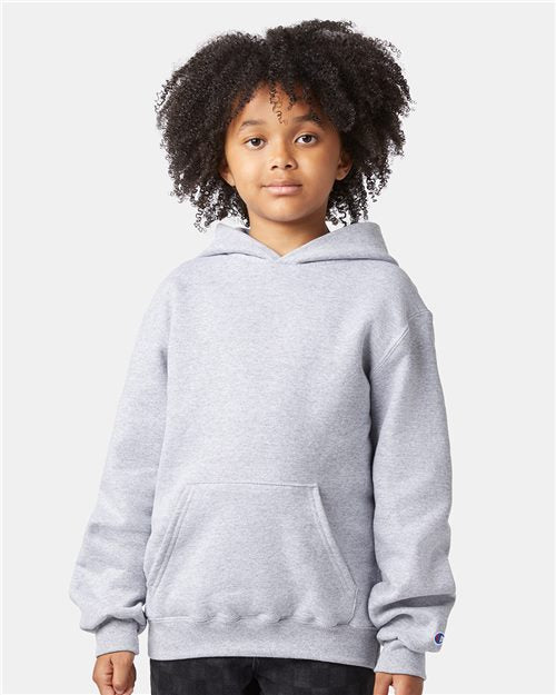 A child with curly hair wears a light gray Champion S790 sweatshirt—a cozy cotton-poly hoodie with a front pocket—standing against a plain light background.
