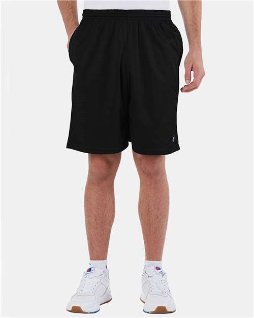 A person wearing Champion S162 athletic shorts stands with hands in pockets; only the lower body is visible, with white socks and sneakers against a plain light background.