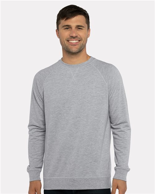 A smiling man with short brown hair wears the Next Level 9000 light gray classic v-notch neck cotton-polyester fleece sweatshirt and dark pants, standing against a plain light background.