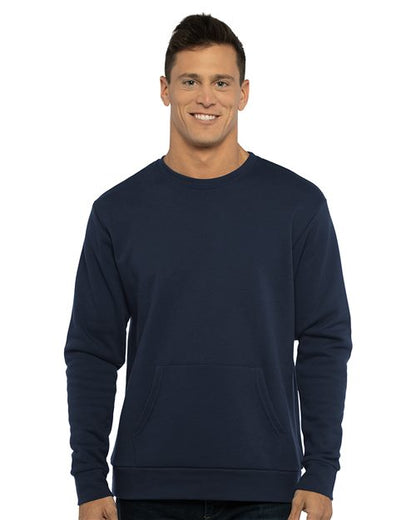 A man with short dark hair smiles, wearing the Next Level 9001 unisex navy blue crewneck sweatshirt made from cotton/polyester fleece with a front pocket, standing against a white background.