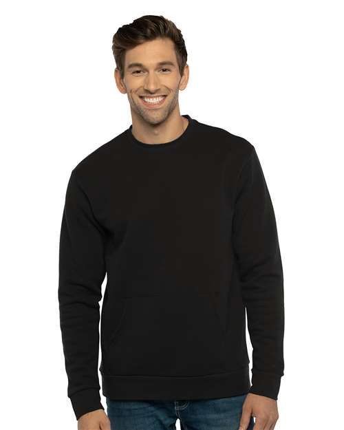 A man with short brown hair smiles while wearing the Next Level 9001 unisex fit plain black sweatshirt, made from cotton/polyester fleece, paired with blue jeans against a white background.