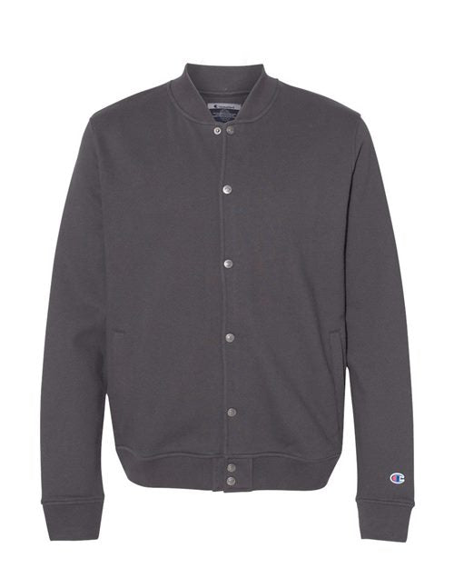 The Champion CO100 is a plain dark gray button-up bomber jacket with side pockets and ribbed cuffs, made from sueded fleece. It features an embroidered Champion logo near the left wrist and is shown on a white background.
