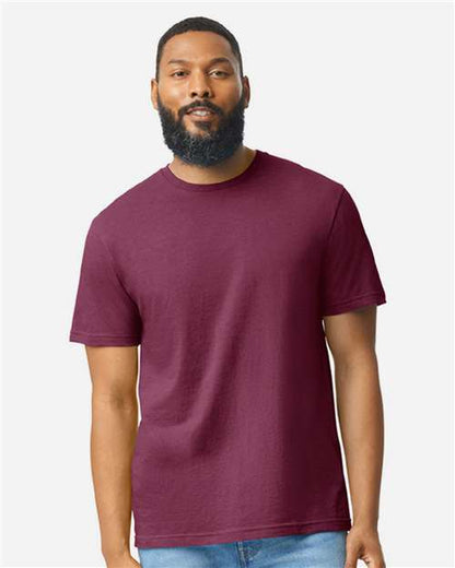 A man wearing a red Gildan Softstyle 64000CVC t-shirt made from ring-spun cotton by Gildan.