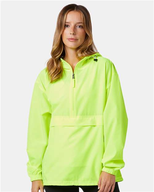 A woman with long, light brown hair wears a neon yellow-green Champion CO200 micro poplin pullover jacket with a front zipper and elastic cuffs, standing against a plain light gray background.