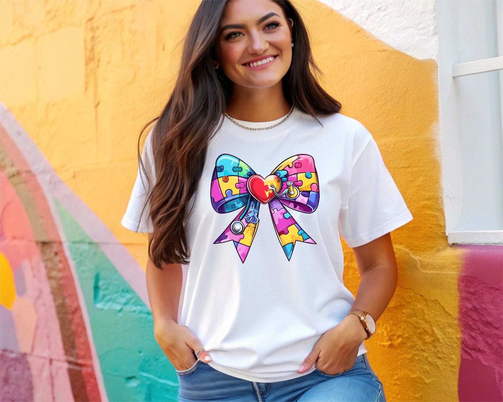 A smiling woman stands by a colorful wall, wearing the Autism Bow t-shirt from DB Custom Creations. It features a vibrant puzzle piece bow with a red heart, printed using 11-inch DTF for vivid, lasting results.