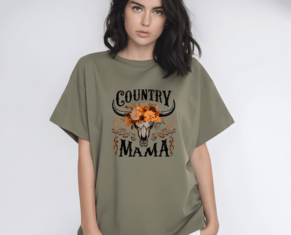 A woman wears the Country Mama T-shirt by DB Custom Creations—an oversized olive green tee with a floral bull skull and Country Mama on the front, made using vibrant, long-lasting DTF printing.