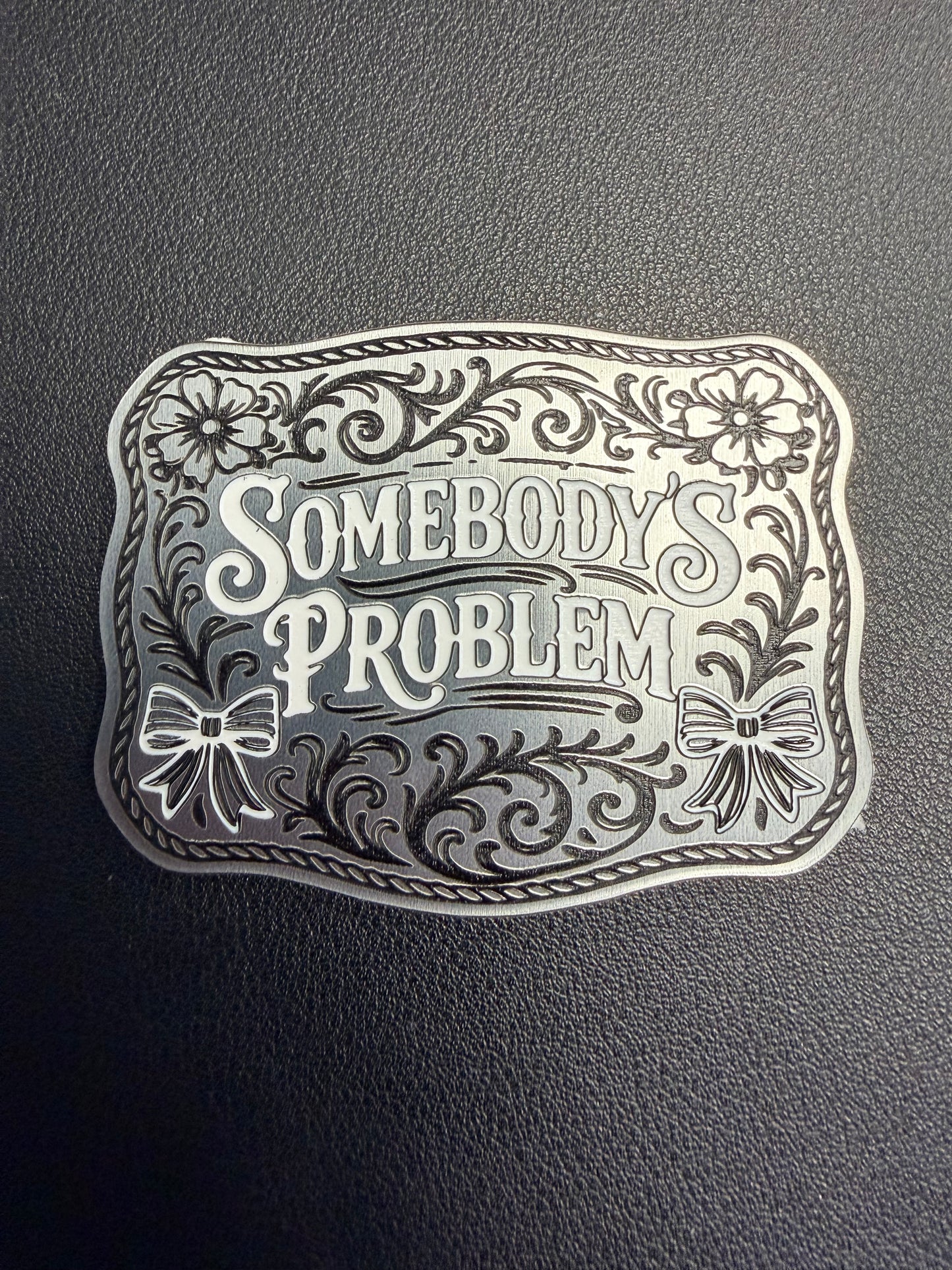 DB Custom Creations’ Custom Laser Engraved Tri Layered Acrylic Patches for Hats feature bold, stylized “Somebody’s Problem” text with floral and ribbon accents—perfect for pairing with contour cut patches or adhesive patches.