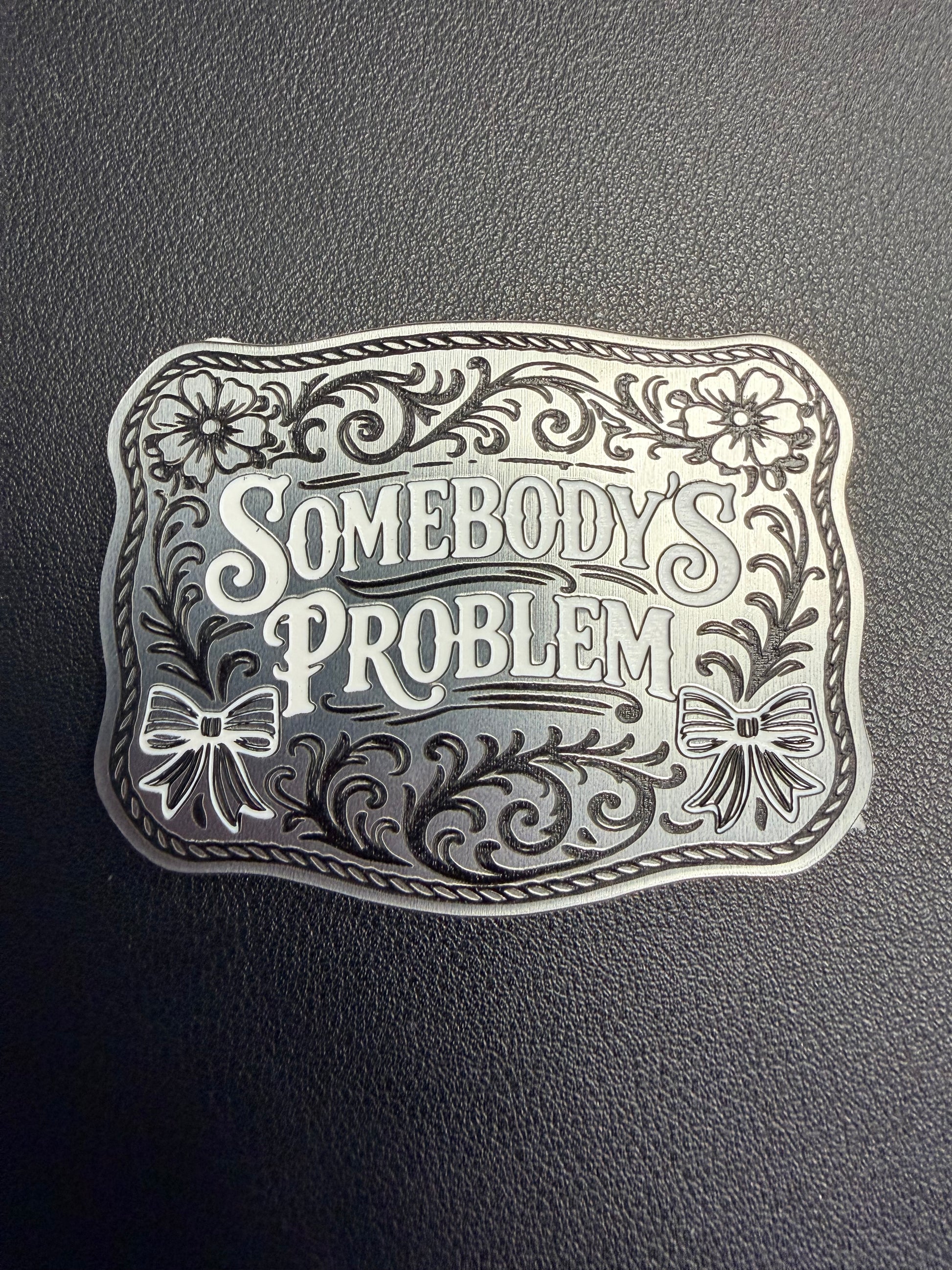 DB Custom Creations’ Custom Laser Engraved Tri Layered Acrylic Patches for Hats feature bold, stylized “Somebody’s Problem” text with floral and ribbon accents—perfect for pairing with contour cut patches or adhesive patches.
