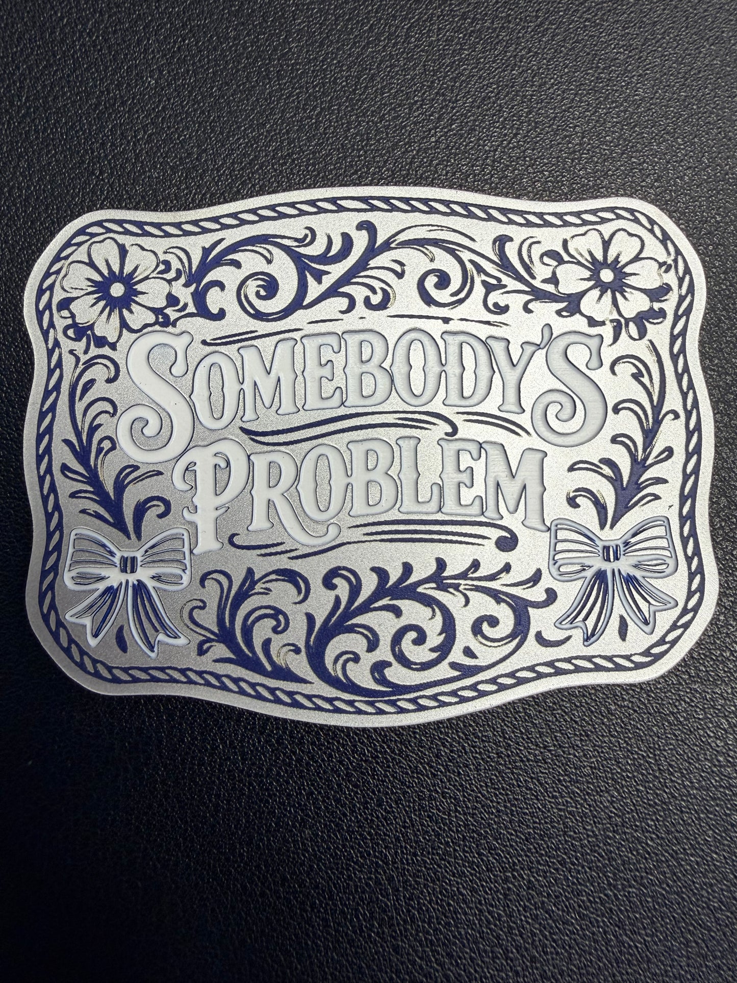 DB Custom Creations' custom laser engraved tri layered acrylic patches for hats showcase bold floral designs, bows, ornate borders, and the phrase "Somebody’s Problem," set on a textured black base with strong adhesive for secure use.