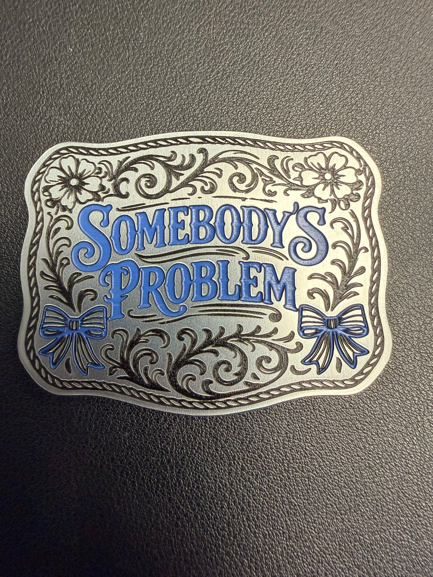 DB Custom Creations' Custom Laser Engraved Tri Layered Acrylic Patch features floral designs, bows, and ornate borders with "Somebodys Problem" in stylized blue and black on a textured dark background, inspired by premium patch aesthetics.