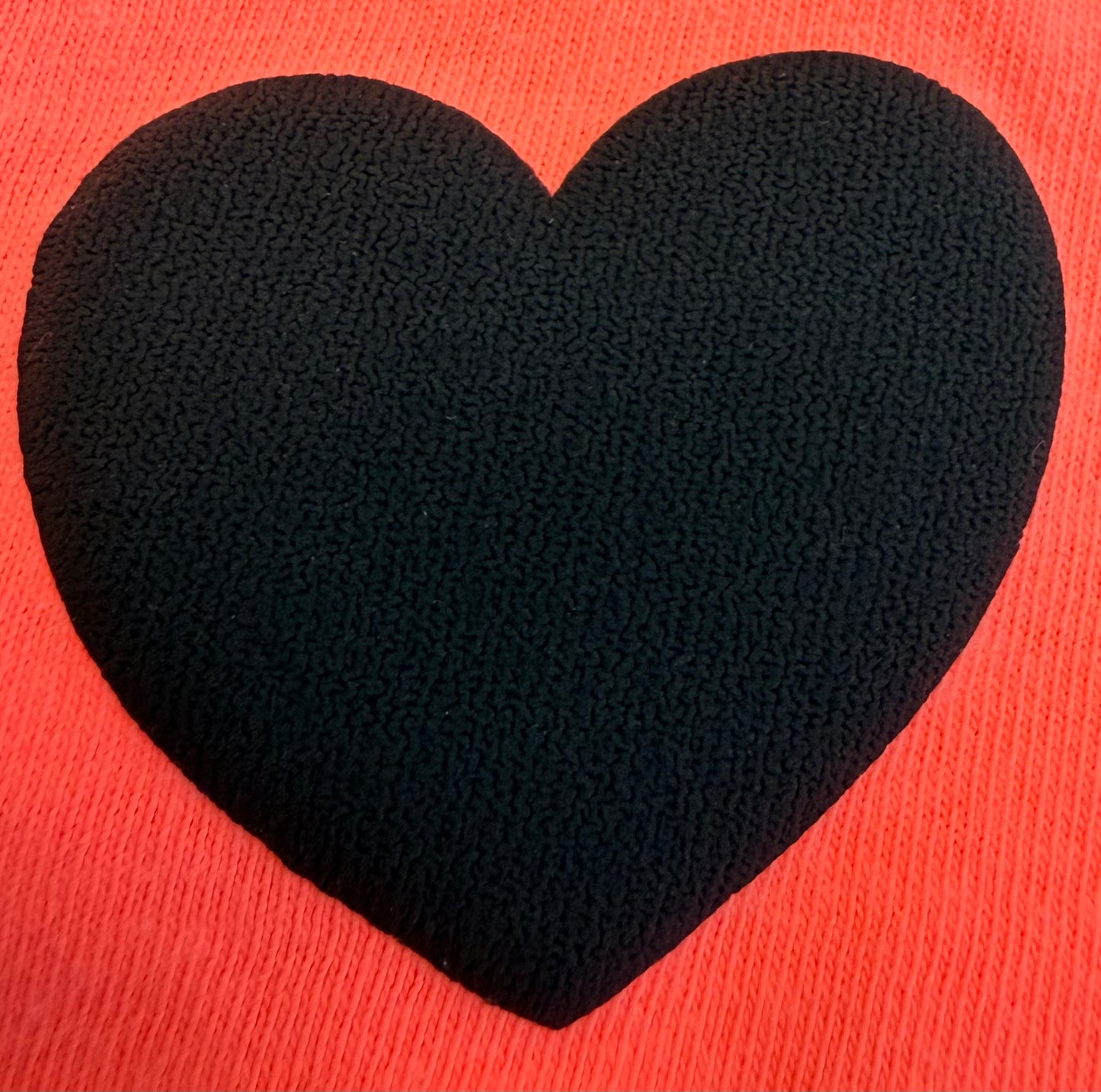 A prominent black heart shape is centered on a vibrant red, textured fabric background, making it ideal for creating bold apparel or unique T-shirt designs with Custom Puff Transfers for T-Shirts and Apparel by DB Custom Creations.