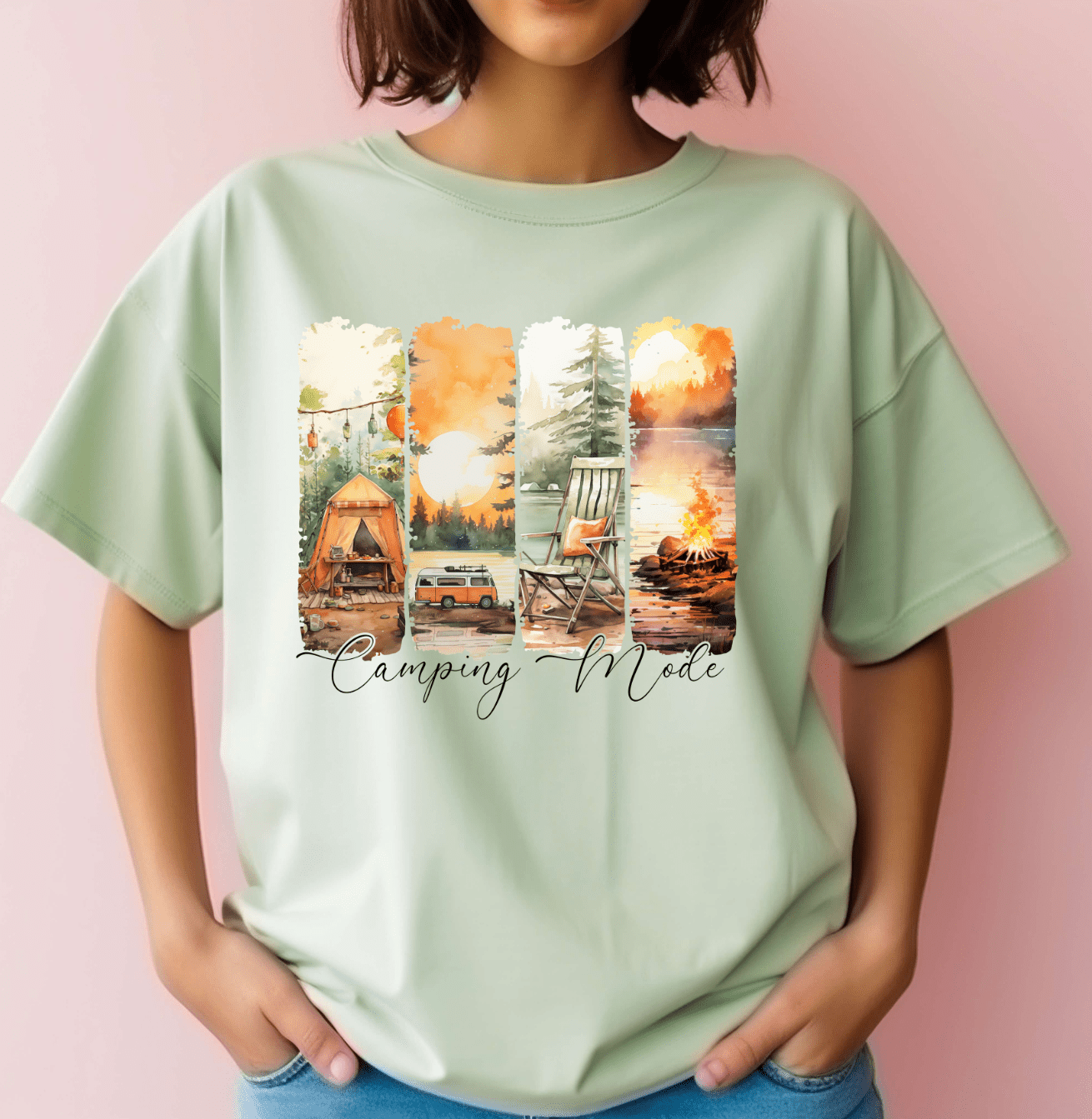 A person wears a light green Camping Mode t-shirt by DB Custom Creations, featuring DTF Transfer images of a tent, car, rocking chair, and campfire in nature with Camping Mode printed below.