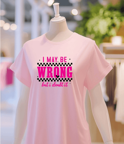 A mannequin models DB Custom Creations May be wrong light pink t-shirt, featuring bold pink and black text, in a brightly lit clothing store.