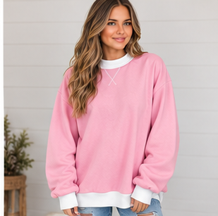 A woman wears a DB Custom Creations Oversized Mock Neck in pink with white cuffs and a white neckline, crafted from premium fabric for everyday wear.