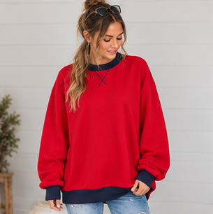 A woman wears a DB Custom Creations Oversized Mock Neck, an oversized red sweatshirt with a navy collar, cuffs, and hem, crafted from premium fabric.