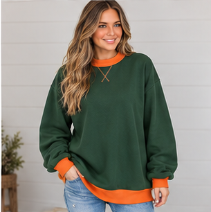 A woman wears a DB Custom Creations Oversized Mock Neck in forest green with an orange collar, cuffs, and hem, crafted from premium fabric.