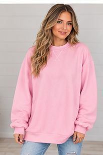 A woman wears a light pink DB Custom Creations Oversized Mock Neck sweatshirt, featuring a mock neck and decorative stitching at the collar for comfortable everyday wear.