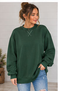 A woman wearing a forest green Oversized Mock Neck sweatshirt featuring decorative stitching at the collar.